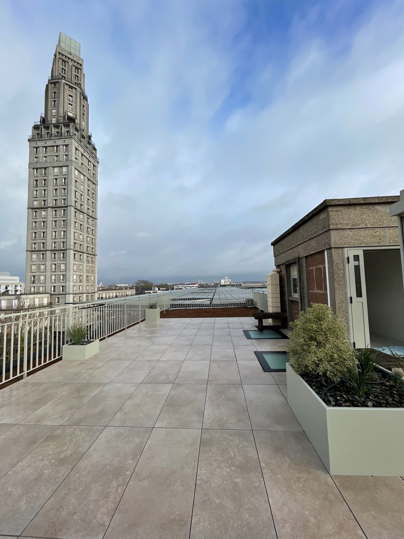 Terrasse sur plots en grès cérame avec vue sur la Tour Perret d'Amiens