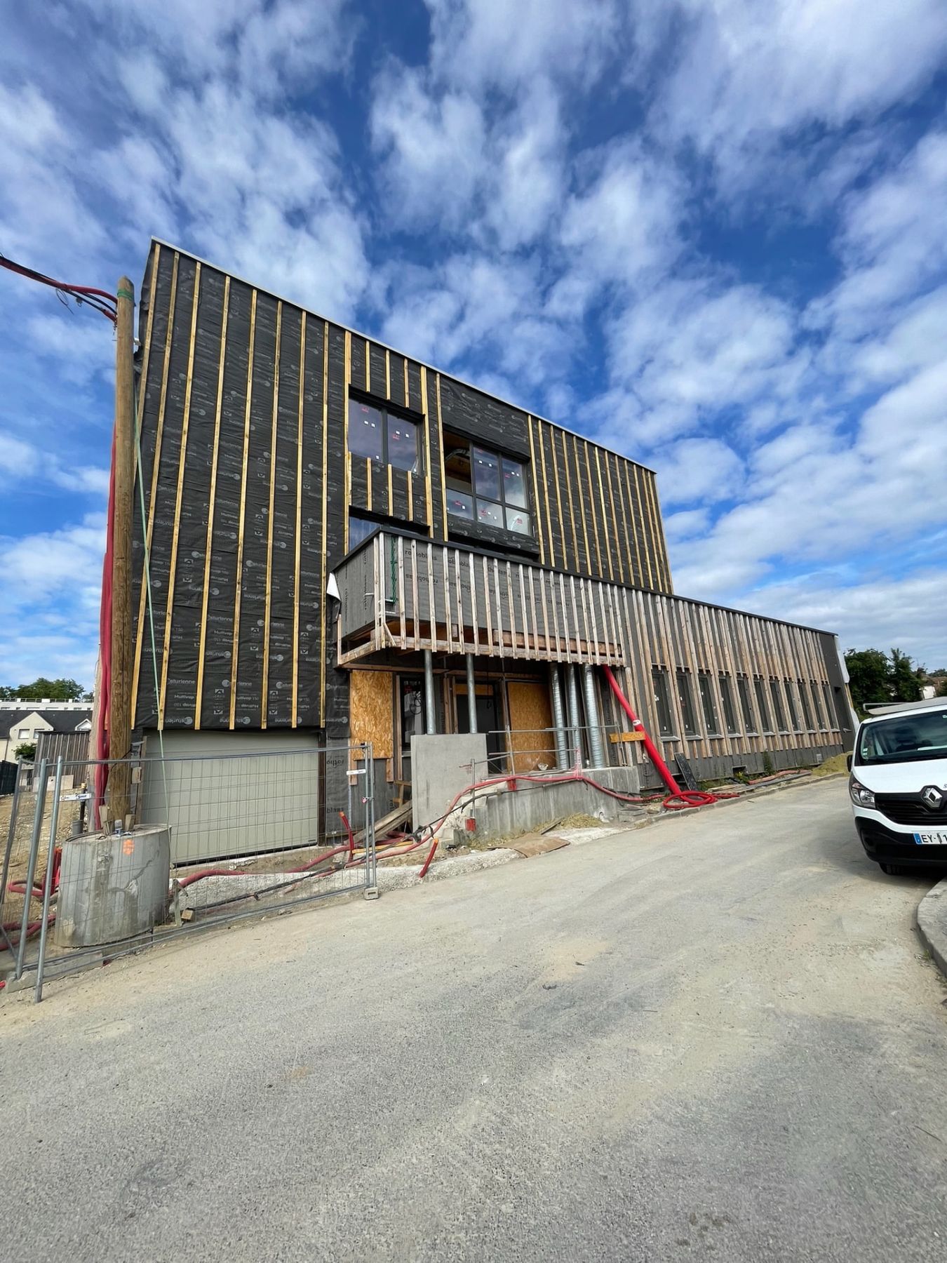 Détail du complexe de façade : pare-pluie noir, ossature bois et bardage en cours de pose