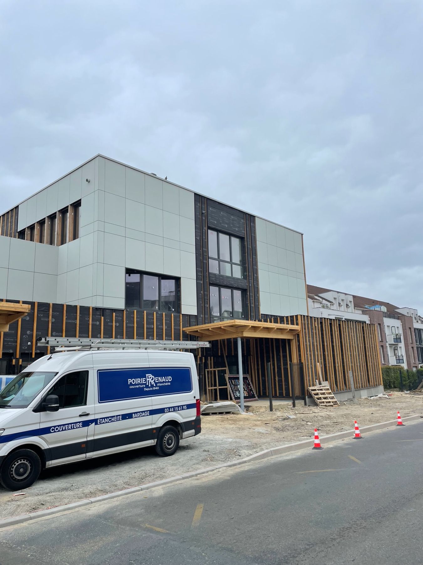 Façade bardée de panneaux composites clairs, camion Renaud Poirier au premier plan