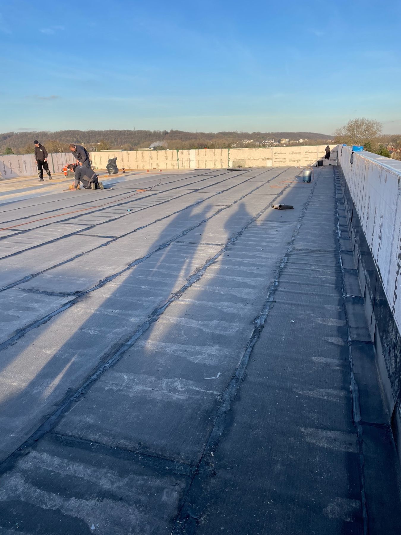Pose de l'étanchéité bitume par passes successives sur toiture-terrasse, vue d'ensemble