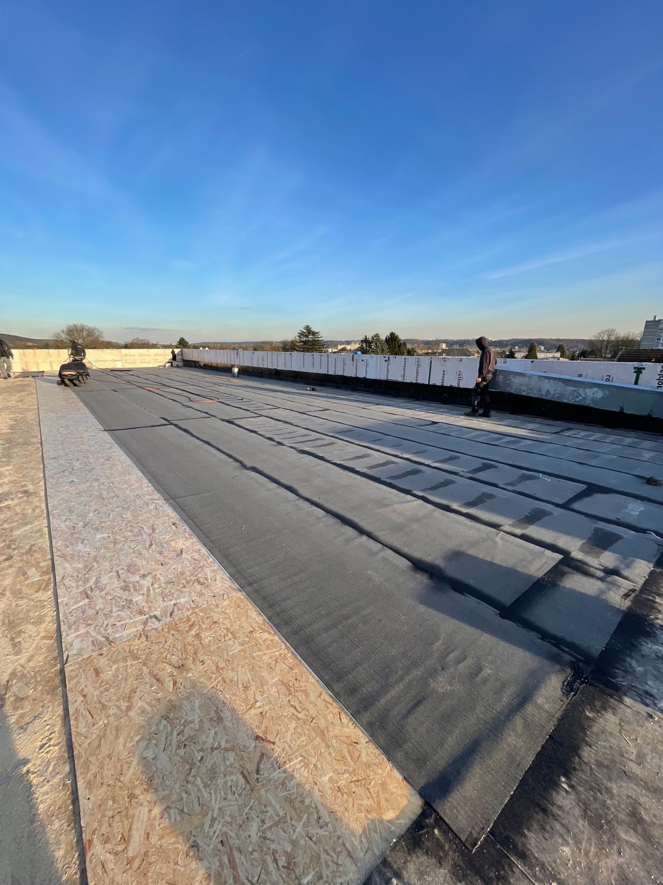 Pose de l'étanchéité bitume par passes successives sur toiture-terrasse, détail des recouvrements