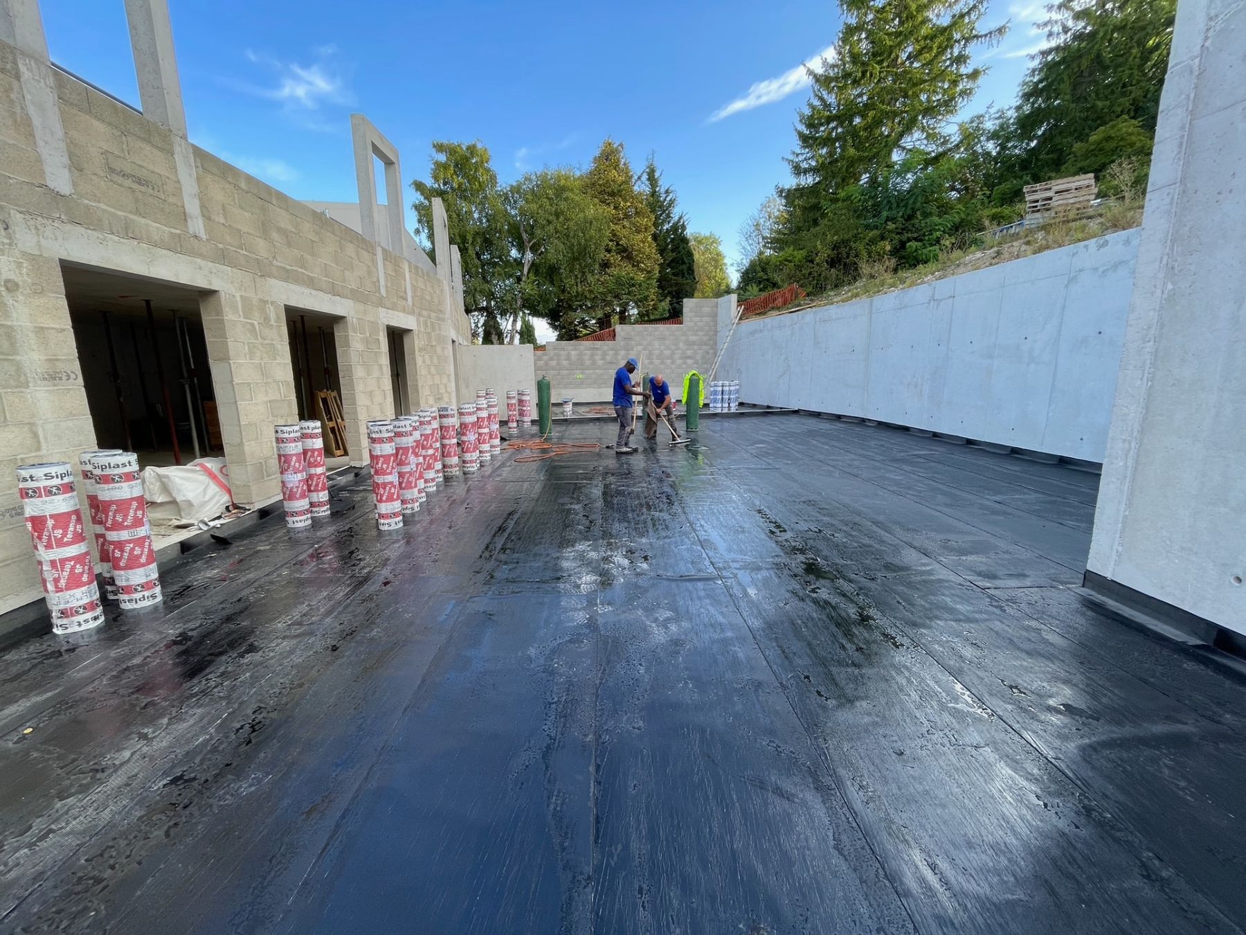 Étancheurs soudant une membrane bitumineuse au chalumeau sur une toiture-terrasse neuve
